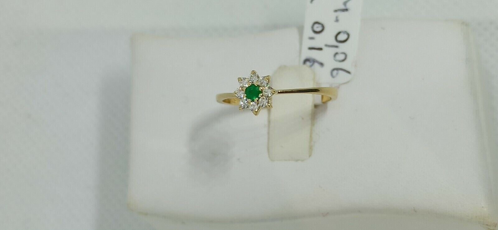 Anello in oro giallo 18 kt con smeraldo tondo e contorno di diamanti.