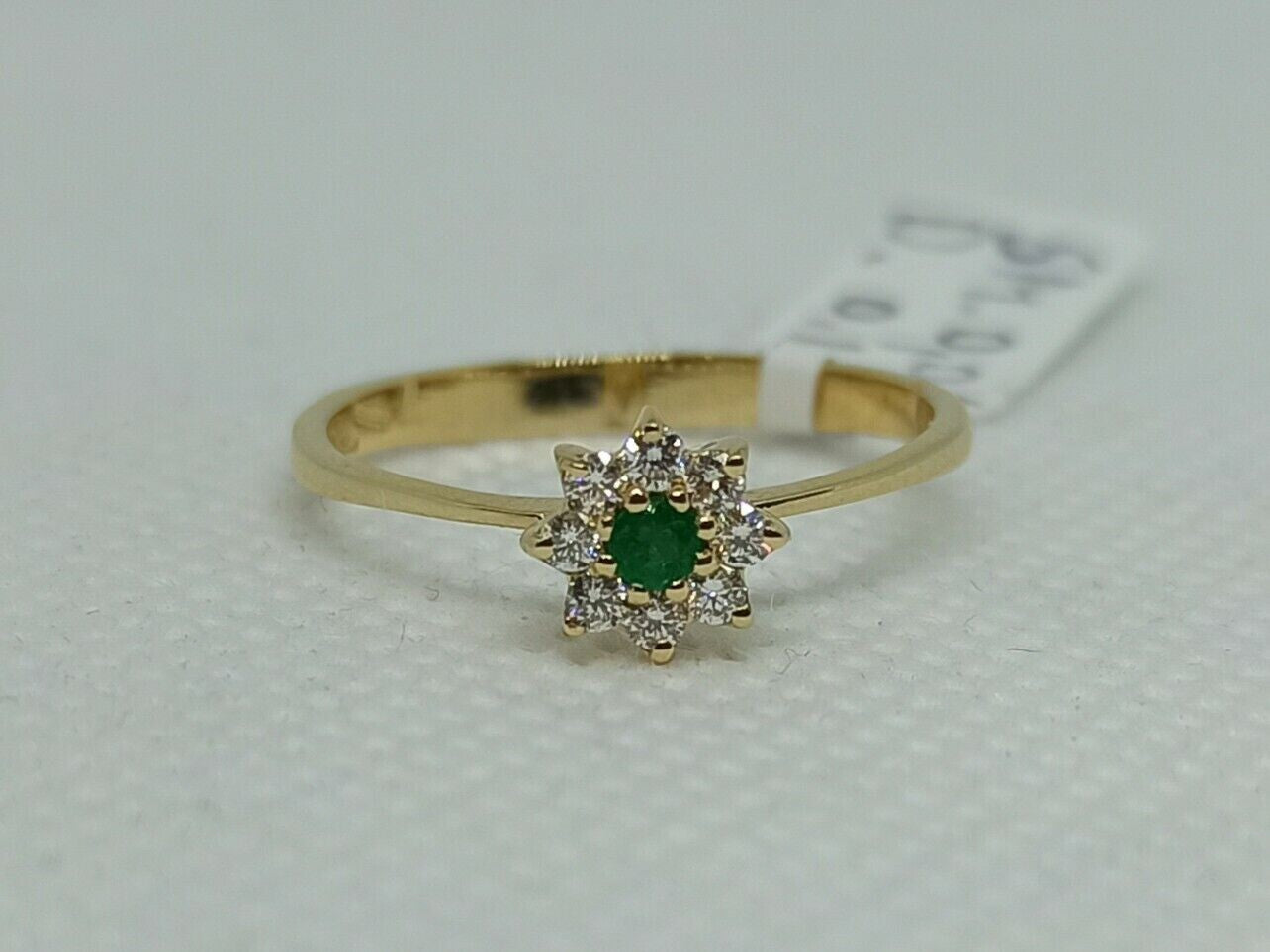 Anello in oro giallo 18 kt con smeraldo tondo e contorno di diamanti.