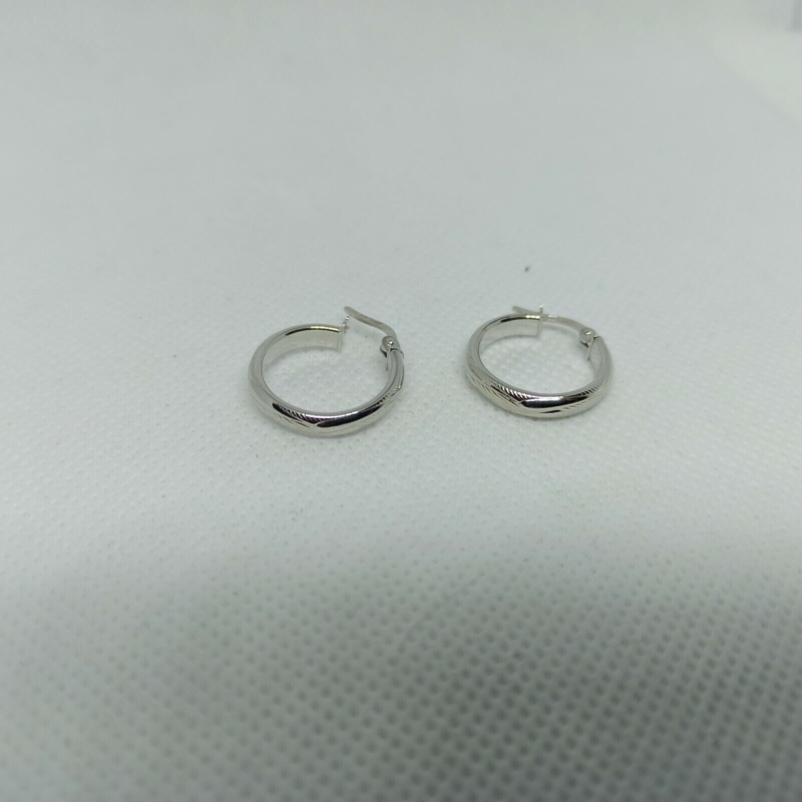 Orecchini a cerchi oro bianco 18 kt  con lavorazione a rilievo e incisioni.