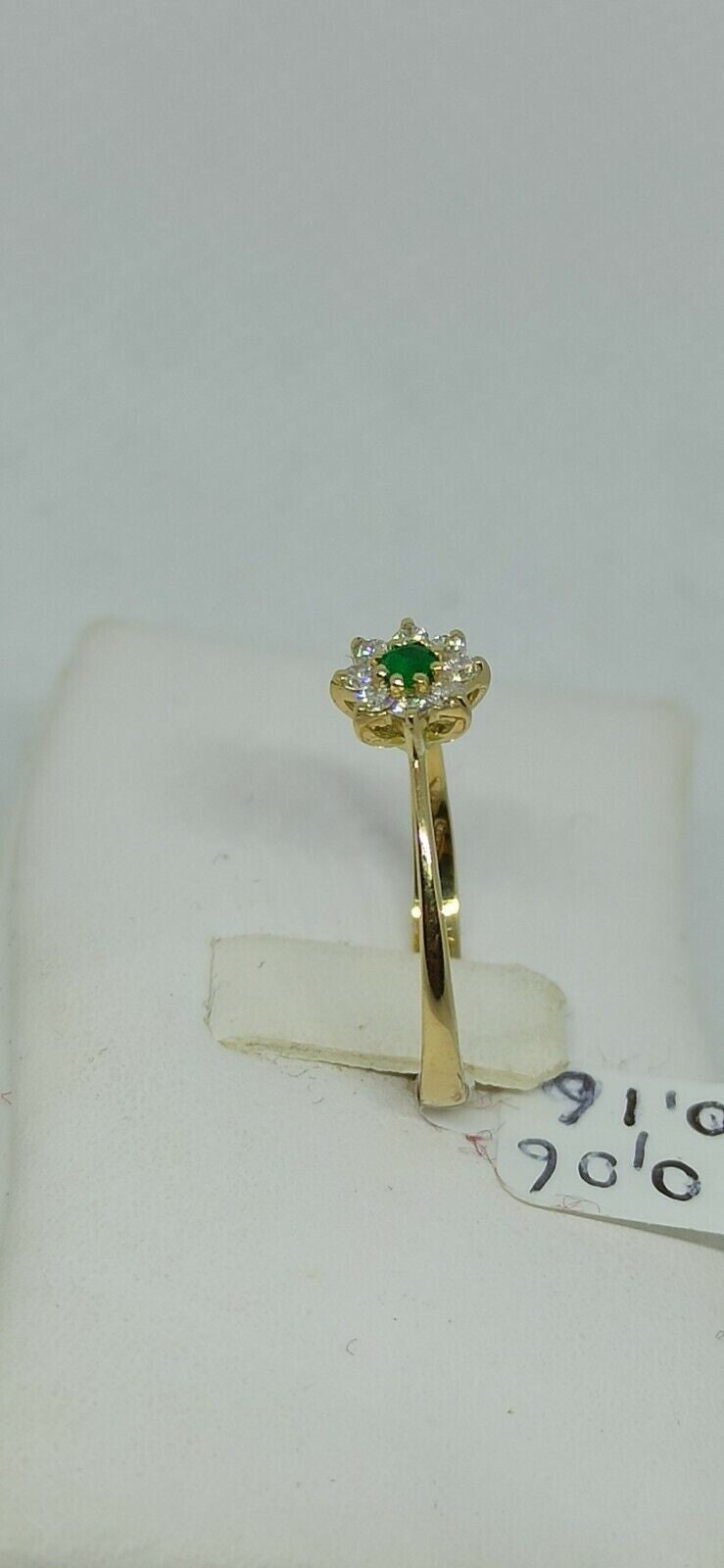 Anello in oro giallo 18 kt con smeraldo tondo e contorno di diamanti.